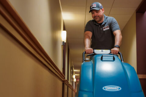 man pushing a floor cleaning machine