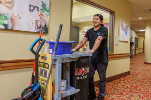 man pushing a cleaning cart smiling