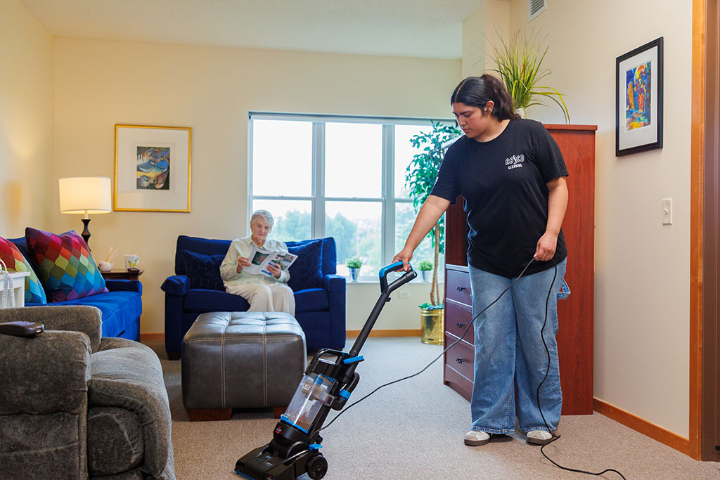 AB\CD employee cleaning a living space with a vacuum